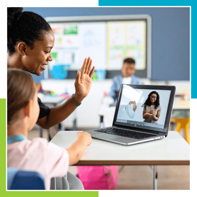 sign lanaguage remote interpreting A teacher and a young student sit together at a classroom desk, interacting with a laptop. On the laptop screen, a person is communicating using sign language during a video call. The classroom setting is bright and colorful, with educational materials visible in the background. This scene highlights the use of technology to support remote learning and sign language communication in an educational environment. Jobs for ASL Interpreters